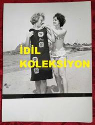 YEŞİLÇAM'IN YILDIZI HÜLYA KOÇYİĞİT'İN ORİJİNAL BÜYÜK BOY FOTOĞRAFI  - 24 x 18 cm EBADINDA - HÜLYA KOÇYİĞİT KUMSALDA SİYAH ELBİSESİNİ GİYMEYE YARDIM ETTİRİRKEN ÇEKİLMİŞ BİR KARE