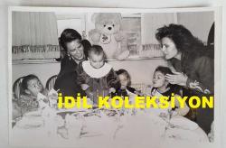 YEŞİLÇAM'IN YILDIZI HÜLYA KOÇYİĞİT'İN ORİJİNAL FOTOĞRAFI  - 18 x 12 cm EBADINDA - HÜLYA KOÇYİĞİT, KIZI GÜLŞAH ALKOÇLAR'IN BEBEĞİ NESLİŞAH'IN BİRİNCİ YAŞ GÜNÜNÜ EV ORTAMINDA KUTLADIĞI ANLARDA TORUNUNA PASTADAKİ MUMLARI ÜFLETİRKEN ÇEKİLMİŞ BİR KARE. 1989