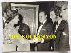 TOM JONES'UN ORİJİNAL BÜYÜK BOY FOTOĞRAFI, İNGİLTERE LONDRA AJANS BASKISI - ORIGINAL PHOTO OF TOM JONES - 22 x 16 cm EBADINDA - KRALİÇE ELIZABETH, 150.000 POUND BAĞIŞ TOPLANAN GECEDE TOM JONES ve KOMEDYEN BOB HOPE'LA TOKALAŞIRKEN ÇEKİLMİŞ ÖZEL BİR KARE. (THE QUEEN ELIZABETH JOINED THE STARS FOR A MILLION-POUND NIGHT AT THE TALK OF THE TOWN WITH RAISED 150,000 POUND. THE QUEEN WAS ACCOMPANIED BY PHILIP, PRINCE CHARLES AND PRINCESS ANNE. AMONG THE GUESTS WERE 17 MEMBERS OF OTHER ROYAL FAMILIES, BUSINESS TYCOONS, STARS - AND MOON-WALKER NEIL ARMSTRONG. PHOTO SHOWS, THE QUEEN SHAKING HANDS WITH TOM JONES AND BOB HOPE LOOKING ON. NOVEMBER 19, 1970)  19 KASIM 1970... İNGİLİZCE HABER METİNLİ. ÖZEL ARŞİV!