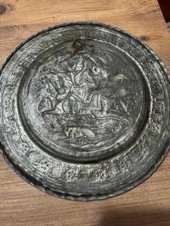 bu tabak, üzerindeki detaylı figürlerle yüksek dekoratif değere sahiptir. Hem koleksiyonluk hem de şık bir duvar aksesuarı arayanlar için kaçırılmayacak bir parçadır. Orta bölümde at üzerinde kılıçlı süvari ve av sahnesi detaylı kabartma (repousse) tekniğiyle işlenmiştir. Tabağın bordür kısmı stilize çiçek ve bitki motifleriyle bezelidir. Bakır üzerine kalay kaplama olup, zamanla oluşan doğal patini sayesinde otantik bir görünüm kazanmıştır. Arkasındaki askı halkası sayesinde duvar dekoru olarak kullanılabilir; şark köşeleri, ofisler veya salonlar için uygundur