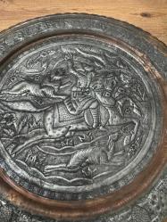 bu tabak, üzerindeki detaylı figürlerle yüksek dekoratif değere sahiptir. Hem koleksiyonluk hem de şık bir duvar aksesuarı arayanlar için kaçırılmayacak bir parçadır. Orta bölümde at üzerinde kılıçlı süvari ve av sahnesi detaylı kabartma (repousse) tekniğiyle işlenmiştir. Tabağın bordür kısmı stilize çiçek ve bitki motifleriyle bezelidir. Bakır üzerine kalay kaplama olup, zamanla oluşan doğal patini sayesinde otantik bir görünüm kazanmıştır. Arkasındaki askı halkası sayesinde duvar dekoru olarak kullanılabilir; şark köşeleri, ofisler veya salonlar için uygundur