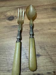 Antika Gümüş İşlemeli Boynuz Servis Takımı Zarafeti ve doğallığı bir arada sunan, koleksiyonluk servis seti (kaşık ve çatal). Özel gün sofralarınıza prestij katacak ya da dekoratif olarak sergilenecek nadide bir parçadır. Tutma yerleri ve uç kısımları doğal boynuz/kemik dokulu özel malzeme. Orta kısımları ince işçilikli, gümüş kaplama kabartma motiflerle bezelidir. Yaşına bağlı hafif bir patina (eskimiş doku) almış olup, herhangi bir kırığı bulunmamaktadır. Vintage/Antika severler için idealdir. Salata servisi veya dekoratif amaçlı uygundur.