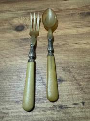 Antika Gümüş İşlemeli Boynuz Servis Takımı Zarafeti ve doğallığı bir arada sunan, koleksiyonluk servis seti (kaşık ve çatal). Özel gün sofralarınıza prestij katacak ya da dekoratif olarak sergilenecek nadide bir parçadır. Tutma yerleri ve uç kısımları doğal boynuz/kemik dokulu özel malzeme. Orta kısımları ince işçilikli, gümüş kaplama kabartma motiflerle bezelidir. Yaşına bağlı hafif bir patina (eskimiş doku) almış olup, herhangi bir kırığı bulunmamaktadır. Vintage/Antika severler için idealdir. Salata servisi veya dekoratif amaçlı uygundur.