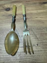 Antika Gümüş İşlemeli Boynuz Servis Takımı Zarafeti ve doğallığı bir arada sunan, koleksiyonluk servis seti (kaşık ve çatal). Özel gün sofralarınıza prestij katacak ya da dekoratif olarak sergilenecek nadide bir parçadır. Tutma yerleri ve uç kısımları doğal boynuz/kemik dokulu özel malzeme. Orta kısımları ince işçilikli, gümüş kaplama kabartma motiflerle bezelidir. Yaşına bağlı hafif bir patina (eskimiş doku) almış olup, herhangi bir kırığı bulunmamaktadır. Vintage/Antika severler için idealdir. Salata servisi veya dekoratif amaçlı uygundur.