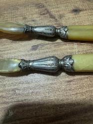 Antika Gümüş İşlemeli Boynuz Servis Takımı Zarafeti ve doğallığı bir arada sunan, koleksiyonluk servis seti (kaşık ve çatal). Özel gün sofralarınıza prestij katacak ya da dekoratif olarak sergilenecek nadide bir parçadır. Tutma yerleri ve uç kısımları doğal boynuz/kemik dokulu özel malzeme. Orta kısımları ince işçilikli, gümüş kaplama kabartma motiflerle bezelidir. Yaşına bağlı hafif bir patina (eskimiş doku) almış olup, herhangi bir kırığı bulunmamaktadır. Vintage/Antika severler için idealdir. Salata servisi veya dekoratif amaçlı uygundur.