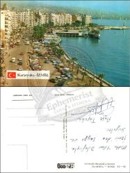 İzmir, Karşıyaka, Kartpostal, 1970’ler: Sahil yolu boyunca park halindeki araçlar, vapur iskelesi, apartmanlar ve körfez görünümü.