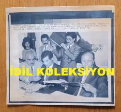 ŞEVKET YILMAZ'IN HABER METİNLİ AJANS-BASIN FOTOĞRAFI (KAĞIT BASKI) - 21 x 19 cm EBADINDA - ŞEVKET YILMAZ, TEKEL'DE 50 BİN KİŞİYİ KAPSAYAN TOPLU SÖZLEŞME İMZALAMA TÖRENİNDE DEVLET BAKANI FAHRETTİN KURT ve ÇALIŞMA BAKANI METİN EMİROĞLU İLE AYNI KAREDE. 1991. HİKMET SAATÇİ