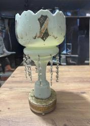 Antika El İşçiliği Kristal Taşlı Opalin Vazo / Obje Evinize klasik bir hava katacak, oldukça zarif ve detaylı bir objedir. Ürün, döneminin estetiğini yansıtan özel süslemelere ve kristal sarkıtlara sahiptir. Gövde üzerinde el işçiliği olduğu anlaşılan altın yaldız ve renkli mine (enamel) işlemeler mevcuttur. Kenarları tırtıklı (scalloped) formdadır. Gövde altından sarkan cam/kristal taşlar ışığı harika yansıtır. Ürünün orijinal ayağı zaman içinde kırıldığı için, görsellerde görülen metal destekli farklı bir ayak ile monte edilmiş. Koleksiyoncular veya evinde nostaljik bir dokunuş arayanlar için kaçırılmayacak şıklıkta bir parçadır.