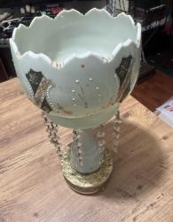 Antika El İşçiliği Kristal Taşlı Opalin Vazo / Obje Evinize klasik bir hava katacak, oldukça zarif ve detaylı bir objedir. Ürün, döneminin estetiğini yansıtan özel süslemelere ve kristal sarkıtlara sahiptir. Gövde üzerinde el işçiliği olduğu anlaşılan altın yaldız ve renkli mine (enamel) işlemeler mevcuttur. Kenarları tırtıklı (scalloped) formdadır. Gövde altından sarkan cam/kristal taşlar ışığı harika yansıtır. Ürünün orijinal ayağı zaman içinde kırıldığı için, görsellerde görülen metal destekli farklı bir ayak ile monte edilmiş. Koleksiyoncular veya evinde nostaljik bir dokunuş arayanlar için kaçırılmayacak şıklıkta bir parçadır.