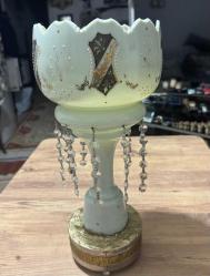 Antika El İşçiliği Kristal Taşlı Opalin Vazo / Obje Evinize klasik bir hava katacak, oldukça zarif ve detaylı bir objedir. Ürün, döneminin estetiğini yansıtan özel süslemelere ve kristal sarkıtlara sahiptir. Gövde üzerinde el işçiliği olduğu anlaşılan altın yaldız ve renkli mine (enamel) işlemeler mevcuttur. Kenarları tırtıklı (scalloped) formdadır. Gövde altından sarkan cam/kristal taşlar ışığı harika yansıtır. Ürünün orijinal ayağı zaman içinde kırıldığı için, görsellerde görülen metal destekli farklı bir ayak ile monte edilmiş. Koleksiyoncular veya evinde nostaljik bir dokunuş arayanlar için kaçırılmayacak şıklıkta bir parçadır.