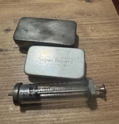 Antika Tıbbi Enjektör ve Metal Kutu Seti Eski dönemlere ait, cam ve metal gövdeli Bayer marka tıbbi enjektör. Üzerinde orijinal yazılar mevcuttur. Yanında 2 adet “Super Record” yazılı metal kutu ile birlikte satılmaktadır. Koleksiyonluk, dekoratif amaçlı veya antika tıp objelerine ilgi duyanlar için idealdir. Kullanım amaçlı değildir. Fotoğraflardaki haliyle gönderilecektir.