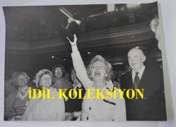 BİRLEŞİK KRALLIK ESKİ BAŞBAKANI MARGARET THATCHER'IN ORİJİNAL FOTOĞRAFI - ORIGINAL PHOTOGRAPH OF FORMER UNITED KINGDOM PRIME MINISTER MARGARET THATCHER - 20 x 15 cm EBADINDA - DÜN MUHAFAZAKAR PARTİ'DE BÜYÜK BİR KARGAŞA YAŞANDI. ŞANS GETİREN SİYAH KEDİ MASKOTU, WESTMİNSTER'DAKİ CENTRAL HALL'DA DÜZENLENEN MUHAFAZAKAR KADINLAR KONFERANSI'NDAN AYRILIRKEN BİR DELEGE TARAFINDAN BAYAN MARGARET THATCHER'A TAKDİM EDİLDİ. SALON, SAĞCI KADINLARIN TERCİH ETTİĞİ TÜYLÜ, ÇİÇEKLİ ŞAPKALARLA DOLUYDU. BAYAN THATCHER, DÜNKÜ TOPLANTIDAN SONRA SİYAH KEDİ MASKOTUNU ELİNDE TUTUYOR. - İNGİLTERE SİYASET TARİHİ - (THIS WAS THE CAT AMONG THE PIGEONS OF THE CONSERVATIVE PARTY YESTERDAY. THE LUCKY BLACK CAT MASCOT WAS PRESENTED BY A DELEGATE TO MRS. MARGARET THATCHER AS SHE LEFT THE CONSERVATIVE WOMEN'S CONFERENCE AT CENTRAL HALL, WESTMINSTER. THE HALL WAS A SEA OF THOSE FEATHERY, FLOWERY HATS FAVOURED BY RIGHT-THINKING WOMEN. MRS THATCHER HOLDING UP THE BLACK CA MASCOT AFTER YESTERDAY MEETING.) - ÖZEL ARŞİV