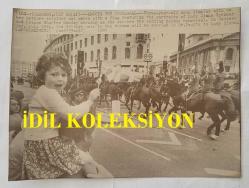 KRAL III. CHARLES'IN (CHARLES PHILIP ARTHUR GEORGE) PRENSES DIANA İLE ORİJİNAL HABER AJANSI BASIM FOTOĞRAFI - NEWS AGENCY PHOTO OF CHARLES III, (CHARLES PHILIP ARTHUR GEORGE) - 23 x 17 cm EBADINDA - ÜÇ YAŞINDAKİ ANNA SİMMİNS, PAZAR SABAHI DÜĞÜN ALAYI PROVASINI İZLERKEN ANNESİNİN OMZUNDA OTURUYOR VE LADY DİANA SPENCER İLE PRENS CHARLES'IN PORTRELERİNİN YER ALDIĞI BİR BAYRAK SALLIYOR. 29 TEMMUZ ÇARŞAMBA GÜNÜ, İNGİLİZ TAHTININ VARİSİ, ST. PAUL KATEDRALİ'NDE LADY DİANA İLE EVLENECEK. 1981. - (THREE-YEAR-OLD ANNA SIMMINS SITS ON HER MOTHERS SHOULDER AND WAVES WITH A FLAG FEATURING THE PORTRAITS OF LADY DIANA SPENCER AND PRINCE CHARLES SUNDAY MORNING AS SHE WATCHES THE WEDDING PARADE REHEARSAL. ON WEDNESDAY, JULY 29TH, THE BRITISH HEIR TO THE THRONE WILL BE MARRIED IN ST. PAUL'S TO LADY DIANA. 1981)