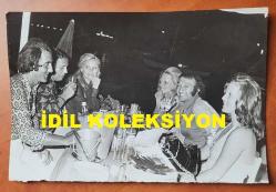 ÖMÜR GÖKSEL'İN ORİJİNAL FOTOĞRAFI - 18 x 12 cm EBADINDA - ÖMÜR GÖKSEL, EŞİ HÜLYA GÖKSEL'LE BİRLİKTE DENİZ KENARINDA MİSAFİRLERİYLE AKŞAM YEMEĞİ YERLERKEN ÇEKİLMİŞ BİR HATIRA FOTOĞRAFI