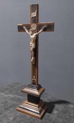 Avrupa, Kaideli İsa Temalı Haç. Kahverengi-Siyah, Üç Katlı, Kısmen Yivli Bir Kaide Üzerinde Duran Bir Haç (Çarmıh). Gövdesi Nikel Gümüşünden Yapılmıştır. Kolları Çapraz Olarak Yukarı Doğru Uzanmaktadır. Gövde, Yukarı Doğru Uzanan Ellerden Geçirilen İki Çivi İle Haçın Enine Kirişine Tutturulmuştur. İki Ayak, Bir Kaide Üzerinde Üst Üste Durmaktadır. Her İki Ayaktan Geçen Çivi Belirtilmiştir. İsa'nın Başının Arkasında/Üstünde Bir Hale (Alev) Bulunmaktadır. Bunun Üzerinde, Kavisli Bir Bant Şeklinde Titulus Crucis (INRI Levhası) Yer Almaktadır. Ayakların Altına, Kemiklerinin Sağ Yarısı Eksik Olan Adem'i Tasvir Eden Metal Bir Kafatası İliştirilmiştir. Bu Siyah Lake Kaplı Ahşap Haçlar Muhtemelen Dini Törenlerde Kullanılmıştır. 1900 Ortaları.