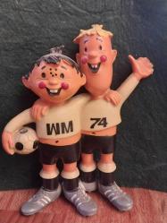 1974 FIFA Dünya Kupası'nın resmi maskotları olan Tip ve Tap 13 x 11 cm. Tarih: 1974 yılında Batı Almanya'da düzenlenen Dünya Kupası için tasarlanmıştır.  Detaylar: Maskotlar, Batı ve Doğu Almanya'yı temsil eden iki kardeştir.  Sembolizm: Üzerlerindeki 