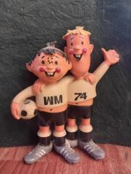 1974 FIFA Dünya Kupası'nın resmi maskotları olan Tip ve Tap 13 x 11 cm. Tarih: 1974 yılında Batı Almanya'da düzenlenen Dünya Kupası için tasarlanmıştır.  Detaylar: Maskotlar, Batı ve Doğu Almanya'yı temsil eden iki kardeştir.  Sembolizm: Üzerlerindeki 