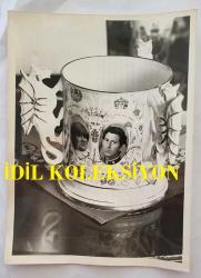 PRENSES DIANA'NIN ORİJİNAL FOTOĞRAFI - ORIGINAL PHOTOGRAPH OF PRINCESS DIANA - 20 x 15 cm EBADINDA - PRENS CHARLES VE LADY DİANA SPENCER'IN PORTRELERİNİ TAŞIYAN BİBLOLARDAN KAÇINMAK, SAĞANAK YAĞMURDA KURU KALMAYA ÇALIŞMAK GİBİDİR. VATANSEVER KAPİTALİZMİN YÜKSELİŞİYLE BİRLİKTE, ÇAY HAVLULARI, PORSELEN KUPALAR, HATIRA DEFTERLERİ, ÇAKI, ANAHTARLIK, ALIŞVERİŞ ÇANTASI, ROZET VE GÜNEŞ GÖZLÜĞÜ ÜRETİCİLERİ, ÖNLÜK, KAŞIK, TİŞÖRT, PİKE VE KALEM KUTUSU ÜRETİCİLERİYLE BİR ARAYA GELEREK, BU YÜZYILIN VEYA HERHANGİ BİR YÜZYILIN -MALİ AÇIDAN- DÜĞÜNÜNÜ KUTLUYORLAR. - AVOIDING TRINKETS BEARING THE PORTRAIT OF PRINCE CHARLES AND LADY DIANA SPENCER IS LIKE TRYING TO STAY DRY IN A DOWNPOUR. IN A SURGE OF PATRIOTIC CAPITALISM, MAKERS OF TEA TOWELS, CHINE MUGS, AUTOGRAPH BOOKS, PENKNIVES, KEY-RINGS, SHOPPING BAGS, BADGES AND LAMBSHADES HAVE JOINED HANDS WITH MANUFACTURERS OD SPRONS, SPOONS, T-SHIRTS, PIAQUES AND PENCIL BOXES TO CELEBRATE THE WEDDING - FINACIALLY SPEAKING - OF THIS OR ANY OTHER CENTURY.