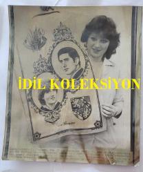PRENSES DIANA'NIN ORİJİNAL HABER AJANSI BASIM FOTOĞRAFI - NEWS AGENCY PHOTO OF PRINCESS DIANA - 25 x 21 cm EBADINDA - BELFAST'TAKİ DOKUMA ŞİRKETİNDE ÇALIŞAN VE HALİHAZIRDA KRALİYET HATIRASI ÇAY HAVLUSU ÜRETEN DİKİŞÇİLERDEN 19 YAŞINDAKİ LORRAİNE BELL, BU SABAH BURADA ÜRÜNÜN BİR ÖRNEĞİNİ SERGİLİYOR. ŞİRKETİN BAŞKANI, BİR KRALİYET AİLESİ ÜYESİNİN BU HAVLUYU SATIN ALMA İHTİMALİNE 500 STERLİN YATIRIM YAPMIŞTI. - LORRAINE BELL, 19, ONE OF THE STITCHERS AT THE BELFAST WEAVING COMPANY WHICH IS ALREADY PRODUCING A ROYAL SOUVENIER TEA TOWEL DISPLAYS A SAMPLE OF THE PRODUCT HERE THIS MORNING. THE COMPANY'S CHAIRMAN RECENTLY GAMBLED 500 POUND ON THE DESIGN ON THE PROSPECT OF A ROYAL.