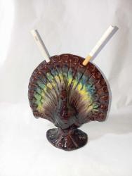 tavus kuşu formunda tasarlanmış antika bir Çanakkale işi sigaralık. 20. yüzyıl başına ait, pişmiş topraktan üretilmiş sırlı bir koleksiyon parçasıdır. 20 sigara kapasitesine sahiptir. Koyu kahverengi, yeşil ve sarı renkli sırlar kullanılarak el işçiliği ile yapılmıştır.