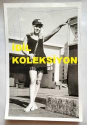 ŞANTÖZ SERPİL SEREN'İN ORİJİNAL FOTOĞRAFI - 18 x 12 cm EBADINDA - SERPİL SEREN, SİYAH MİNİ ELBİSESİYLE Akaryakıt istasyonunda pompacı kadın personel olarak POZ VERİRKEN ÇEKİLMİŞ BİR KARE