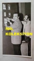 TRT İSTANBUL RADYOSU SES SANATÇISI ve KORO ŞEFİ BÜLENT ORAL'IN ORİJİNAL FOTOĞRAFI - 17 x 10 cm EBADINDA - BÜLENT ORAL, PANODAKİ FOTOĞRAFLARINA BAKARKEN ÇEKİLMİŞ BİR KARE