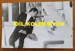 YEŞİLÇAM'IN YILDIZI HÜLYA KOÇYİĞİT'İN ORİJİNAL 2'Lİ FOTOĞRAF SETİ  - 18 x 12 cm EBADINDA - HÜLYA KOÇYİĞİT, EŞİ SELİM SOYDAN'LA BİRLİKTE GELİN ve DAMAT OLARAK, ANNESİ MELEK KOÇYİĞİT'İ HASTA YATAĞINDA ZİYARET EDERKEN ÇEKİLMİŞ 2 FARKLI KARE