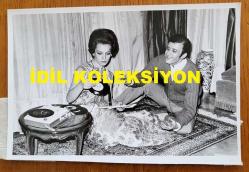 YEŞİLÇAM'IN YILDIZI HÜLYA KOÇYİĞİT'İN ORİJİNAL FOTOĞRAFI - 18 x 12 cm EBADINDA - HÜLYA KOÇYİĞİT, KUDRET ŞANDRA'NIN KENDİSİNE EV ORTAMINDA 45'LİK PLAKLARINI GÖSTERDİĞİ ANLARDA ÇEKİLMİŞ BİR KARE