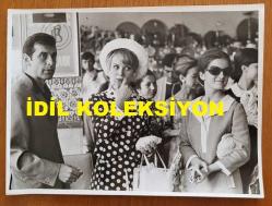YEŞİLÇAM'IN YILDIZI HÜLYA KOÇYİĞİT'İN ORİJİNAL BÜYÜK BOY FOTOĞRAFI - 24 x 18 cm EBADINDA - HÜLYA KOÇYİĞİT ve EŞİ SELİM SOYDAN, HAVA LİMANINDA KENDİLERİNİ YOLCU EDEN FERYAL KOÇYİĞİT'LE AYNI KAREDELERKEN ÇEKİLMİŞ BİR FOTOĞRAF