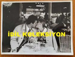 YEŞİLÇAM'IN YILDIZI HÜLYA KOÇYİĞİT'İN ORİJİNAL BÜYÜK BOY FOTOĞRAFI - 24 x 18 cm EBADINDA - HÜLYA KOÇYİĞİT ve EŞİ SELİM SOYDAN, AVRUPA SEYAHATLERİ SIRASINDA YEMEK YEDİKLERİ BİR MEKANDA ÖPÜŞÜRLERKEN ÇEKİLMİŞ ROMANTİK BİR KARE