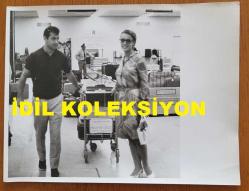 YEŞİLÇAM'IN YILDIZI HÜLYA KOÇYİĞİT'İN ORİJİNAL BÜYÜK BOY FOTOĞRAFI - 24 x 18 cm EBADINDA - HÜLYA KOÇYİĞİT ve EŞİ SELİM SOYDAN, FRANSA PARİS SEYAHATLERİ SIRASINDA HAVA LİMANINDAN VALİZLERİNİ TAŞIRLARKEN ÇEKİLMİŞ BİR KARE (AIRPORT DE PARIS)