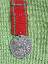 Kılıçlı Gümüş Liyakat Madalyası.. H.1332 M. 1916 Tarihli Gümüş Kılıçlı APARATI Olan Koleksiyonluk Liyakat Madalyası..  1890 tarihli Osmanlı dönemi Liyakat Madalyası. Üzerinde Osmanlı tuğrası, silah ve sancak motiflerinden oluşan devlet arması bulunan bu madalya, arka yüzünde Osmanlıca hat ile yazılmış metni ve altında 1308 (1890/1891) tarihini taşımaktadır. Osmanlı Devleti'nde liyakat ve hizmet karşılığı verilen bu madalyalar, devlet görevlileri ve askerî hizmet sahiplerine takdim edilirdi. Tarihi ve koleksiyon değeri yüksek olan bu eser, Osmanlı nişan ve madalya koleksiyonları için dikkat çekici nadir örneklerden biridir.