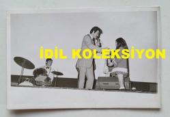ŞARKICI BERKANT'IN ORİJİNAL FOTOĞRAFI - 14 x 9 cm EBADINDA - BERKANT, SAHNEDE KENDİSİNE BİR ŞİŞE ŞARAP GETİREN KÜÇÜK BİR KIZ ÇOCUĞUYLA AYNI KAREDE. (FOTO ŞABAN, ŞABAN ERDEM)