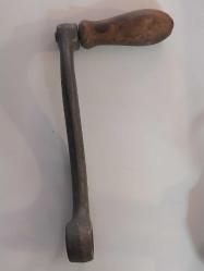 El Krankı, Bu görseldeki nesne, eski dikiş makineleri, fonograflar veya diğer mekanik cihazlar için kullanılan antik bir el krankıdır.  Malzeme: Genellikle dökme demir veya metalden üretilmiş sağlam bir gövdeye sahiptir.  Özellik: Döner bir ahşap veya plastik tutamağı bulunur.  İşlev: Döndürme hareketini mekanik enerjiye çevirerek makineyi manuel olarak çalıştırmak için kullanılır.  Kullanım Alanı: Vintage dikiş makineleri, müzik kutuları veya eski el aletleri için yedek parça veya koleksiyon objesi olarak değerlidir.