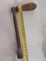 El Krankı, Bu görseldeki nesne, eski dikiş makineleri, fonograflar veya diğer mekanik cihazlar için kullanılan antik bir el krankıdır.  Malzeme: Genellikle dökme demir veya metalden üretilmiş sağlam bir gövdeye sahiptir.  Özellik: Döner bir ahşap veya plastik tutamağı bulunur.  İşlev: Döndürme hareketini mekanik enerjiye çevirerek makineyi manuel olarak çalıştırmak için kullanılır.  Kullanım Alanı: Vintage dikiş makineleri, müzik kutuları veya eski el aletleri için yedek parça veya koleksiyon objesi olarak değerlidir.