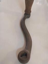 El Krankı, Bu görseldeki nesne, eski dikiş makineleri, fonograflar veya diğer mekanik cihazlar için kullanılan antik bir el krankıdır.  Malzeme: Genellikle dökme demir veya metalden üretilmiş sağlam bir gövdeye sahiptir.  Özellik: Döner bir ahşap veya plastik tutamağı bulunur.  İşlev: Döndürme hareketini mekanik enerjiye çevirerek makineyi manuel olarak çalıştırmak için kullanılır.  Kullanım Alanı: Vintage dikiş makineleri, müzik kutuları veya eski el aletleri için yedek parça veya koleksiyon objesi olarak değerlidir.