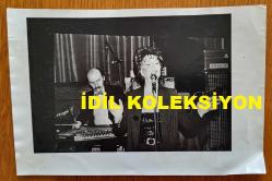 TÜRK SANAT MÜZİĞİ SANATÇISI SEVİM DERAN'IN ORİJİNAL AJANS-BASIN FOTOĞRAFI - 18 x 12 cm EBADINDA  - SEVİM DERAN, SAHNEDE ŞARKI OKUDUĞU SIRADA EŞİ EROL DERAN KANUN ÇALARKEN ÇEKİLMİŞ BİR KARE