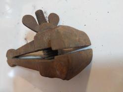 El Mengenesi. Osmanlı dönemine ait el yapımı bir el mengenesi (hand vice) koleksiyon parçasıdır.  Tarihi Değer: Genellikle dövme demirden üretilen bu tür aletler, antika ve koleksiyon değeri taşır.  Kullanım Alanı: Küçük parçaları tutmak, sıkıştırmak veya zımparalama/eğeleme işlemleri sırasında sabit tutmak için kullanılırdı.  Özellikleri: Görseldeki örnekte, parçayı sabitlemek için kullanılan klasik bir vida mekanizması ve yay bulunmaktadır.  Kullanım Amaçları: Takı yapımı, saat tamiri veya küçük metal parçaların işlenmesi gibi hassas işlerde yaygındı.