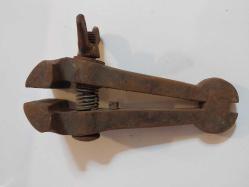 El Mengenesi. Osmanlı dönemine ait el yapımı bir el mengenesi (hand vice) koleksiyon parçasıdır.  Tarihi Değer: Genellikle dövme demirden üretilen bu tür aletler, antika ve koleksiyon değeri taşır.  Kullanım Alanı: Küçük parçaları tutmak, sıkıştırmak veya zımparalama/eğeleme işlemleri sırasında sabit tutmak için kullanılırdı.  Özellikleri: Görseldeki örnekte, parçayı sabitlemek için kullanılan klasik bir vida mekanizması ve yay bulunmaktadır.  Kullanım Amaçları: Takı yapımı, saat tamiri veya küçük metal parçaların işlenmesi gibi hassas işlerde yaygındı.