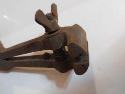 El Mengenesi. Osmanlı dönemine ait el yapımı bir el mengenesi (hand vice) koleksiyon parçasıdır.  Tarihi Değer: Genellikle dövme demirden üretilen bu tür aletler, antika ve koleksiyon değeri taşır.  Kullanım Alanı: Küçük parçaları tutmak, sıkıştırmak veya zımparalama/eğeleme işlemleri sırasında sabit tutmak için kullanılırdı.  Özellikleri: Görseldeki örnekte, parçayı sabitlemek için kullanılan klasik bir vida mekanizması ve yay bulunmaktadır.  Kullanım Amaçları: Takı yapımı, saat tamiri veya küçük metal parçaların işlenmesi gibi hassas işlerde yaygındı.