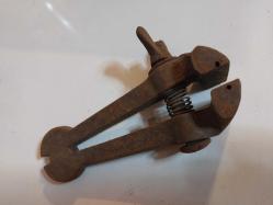 El Mengenesi. Osmanlı dönemine ait el yapımı bir el mengenesi (hand vice) koleksiyon parçasıdır.  Tarihi Değer: Genellikle dövme demirden üretilen bu tür aletler, antika ve koleksiyon değeri taşır.  Kullanım Alanı: Küçük parçaları tutmak, sıkıştırmak veya zımparalama/eğeleme işlemleri sırasında sabit tutmak için kullanılırdı.  Özellikleri: Görseldeki örnekte, parçayı sabitlemek için kullanılan klasik bir vida mekanizması ve yay bulunmaktadır.  Kullanım Amaçları: Takı yapımı, saat tamiri veya küçük metal parçaların işlenmesi gibi hassas işlerde yaygındı.