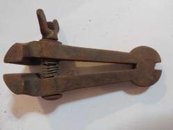 El Mengenesi. Osmanlı dönemine ait el yapımı bir el mengenesi (hand vice) koleksiyon parçasıdır.  Tarihi Değer: Genellikle dövme demirden üretilen bu tür aletler, antika ve koleksiyon değeri taşır.  Kullanım Alanı: Küçük parçaları tutmak, sıkıştırmak veya zımparalama/eğeleme işlemleri sırasında sabit tutmak için kullanılırdı.  Özellikleri: Görseldeki örnekte, parçayı sabitlemek için kullanılan klasik bir vida mekanizması ve yay bulunmaktadır.  Kullanım Amaçları: Takı yapımı, saat tamiri veya küçük metal parçaların işlenmesi gibi hassas işlerde yaygındı.