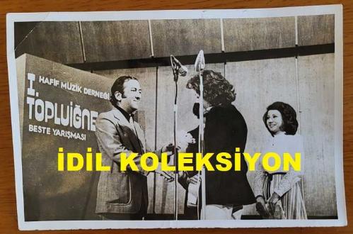 ŞARKICI ve SÖZ YAZARI NİLÜFER'İN ORİJİNAL AJANS-BASIN FOTOĞRAFI (NİLÜFER YUMLU) - 18 x 12 cm EBADINDA - NİLÜFER, HAFİF MÜZİK DERNEĞİ TOPLUİĞNE BESTE YARIŞMASI'NDA İKİNCİ OLAN TUĞRUL DOĞU'YA ÖDÜLÜNÜ VERİRKEN ÇEKİLMİŞ BİR KARE. 30 MAYIS 1974