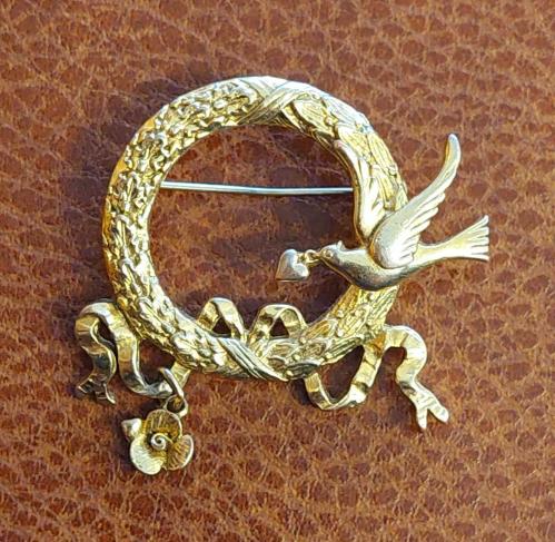 Avrupa, Kalp Taşıyan Kuş Temalı Yaka Broş'u. Altın Tonlu Zarif Bir Ürün (Sallantılı). Kalp ve Çiçeklerle Süslenmiş. Çelenk Bağlantılı, Klipsli İğne. Korunmuş ve İyi Durumda. 1970-1980'ler den. (Anneler Günü ve Sevgiler Günü İçin Mükemmel Bir Hediye.)