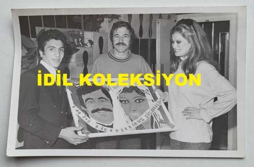 OYUNCU ve SES SANATÇISI SERPİL ÖRÜMCER'İN ORİJİNAL FOTOĞRAFI - 14 x 9 cm EBADINDA - SERPİL ÖRÜMCER, EŞİ ŞARKICI BERKANT'LA BİRLİKTE YAĞLI BOYA RESMİNİ YAPAN RESSAM TARAFINDAN VERİLEN HEDİYEYİ BERKANT'LA BİRLİKTE SAHNEDE ALIRKEN ÇEKİLMİŞ BİR KARE