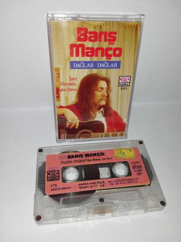 Kaset Barış Manço dağlar dağlar, işte hendek işte deve. Orijinal. 1986 Harika kasetçilik dönem Kağıt Baskı. A6 dağlar dağlar şarkısında 2 saniye kayıp var. Kartonet tertemiz  Kaset gövdesi üzerindeki etiket farklılığının nedeni; özellikle 80'li ve 90'lı yıllarda kaset firmaları tarafından satmayan kağıt baskı kasetlerin üzerine yeni kağıt yapıştırılıp piyasaya sürülürdü. Bu durum tamamen o dönemin malzeme değerlendirme ve stok eritme yöntemlerinden kaynaklanan, kasetin orijinalliğini ve dönem ruhunu bozmayan bir detaydır. Koleksiyoncular için farklı bir örnektir.