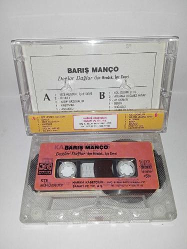 Kaset Barış Manço dağlar dağlar, işte hendek işte deve. Orijinal. 1986 Harika kasetçilik dönem Kağıt Baskı. A6 dağlar dağlar şarkısında 2 saniye kayıp var. Kartonet tertemiz  Kaset gövdesi üzerindeki etiket farklılığının nedeni; özellikle 80'li ve 90'lı yıllarda kaset firmaları tarafından satmayan kağıt baskı kasetlerin üzerine yeni kağıt yapıştırılıp piyasaya sürülürdü. Bu durum tamamen o dönemin malzeme değerlendirme ve stok eritme yöntemlerinden kaynaklanan, kasetin orijinalliğini ve dönem ruhunu bozmayan bir detaydır. Koleksiyoncular için farklı bir örnektir.