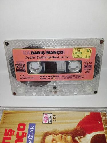 Kaset Barış Manço dağlar dağlar, işte hendek işte deve. Orijinal. 1986 Harika kasetçilik dönem Kağıt Baskı. A6 dağlar dağlar şarkısında 2 saniye kayıp var. Kartonet tertemiz  Kaset gövdesi üzerindeki etiket farklılığının nedeni; özellikle 80'li ve 90'lı yıllarda kaset firmaları tarafından satmayan kağıt baskı kasetlerin üzerine yeni kağıt yapıştırılıp piyasaya sürülürdü. Bu durum tamamen o dönemin malzeme değerlendirme ve stok eritme yöntemlerinden kaynaklanan, kasetin orijinalliğini ve dönem ruhunu bozmayan bir detaydır. Koleksiyoncular için farklı bir örnektir.