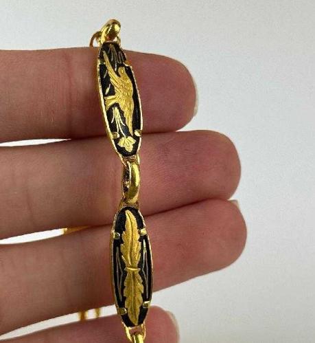 TOLEDO BİLEKLİK,  İspanyol Toledo - Kuş ve Çiçek Motifli Altın Kakma Damascene El İşçilikli - Vintage Bileklik Mağazamızda sizlerle buluşan bu detaylı bileklik, geleneksel Damascene (Şam işi) metal süsleme sanatının karakteristik özelliklerini yansıtıyor. Siyah zemin üzerine altın rengi işlemelerle bezenmiş bu takı, üzerindeki kuş ve çiçek motifleriyle vintage obje meraklılarının dikkatini çekiyor. Kendi döneminin el işçiliği geleneğini günümüze taşıyan bu tasarım, koleksiyonlar için kültürel bir değer taşıyor. Geleneksel motifleri üzerinde barındıran bu aksesuara koleksiyonunuzda yer açmalısınız..