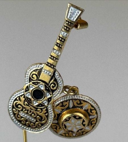 İspanyol Üretim Toledo - Gitar ve Sombrero Figürlü Altın Kakma Damascene El İşçilikli Pirinç - Vintage Broş. İspanyol el işçiliğinin zarif bir örneği olan Toledo üretimi gitar ve sombrero tasarımlı broş, mağazamızda koleksiyonerlerin beğenisine sunuluyor. Geleneksel metal işleme sanatının ince detaylarını taşıyan bu özel yaka iğnesi, siyah zemin üzerine işlenen altın ve gümüş renkli motifleriyle dikkat çekiyor. Döneminin karakteristik takı modasını ve İspanyol kültürünün sıcaklığını yansıtan bu parça, vintage takı koleksiyonlarına anlam katıyor. Giyim tarzınıza nostaljik bir dokunuş yapmak veya koleksiyonunuzu zenginleştirmek için bu özel tasarıma hemen sahip olabilirsiniz..